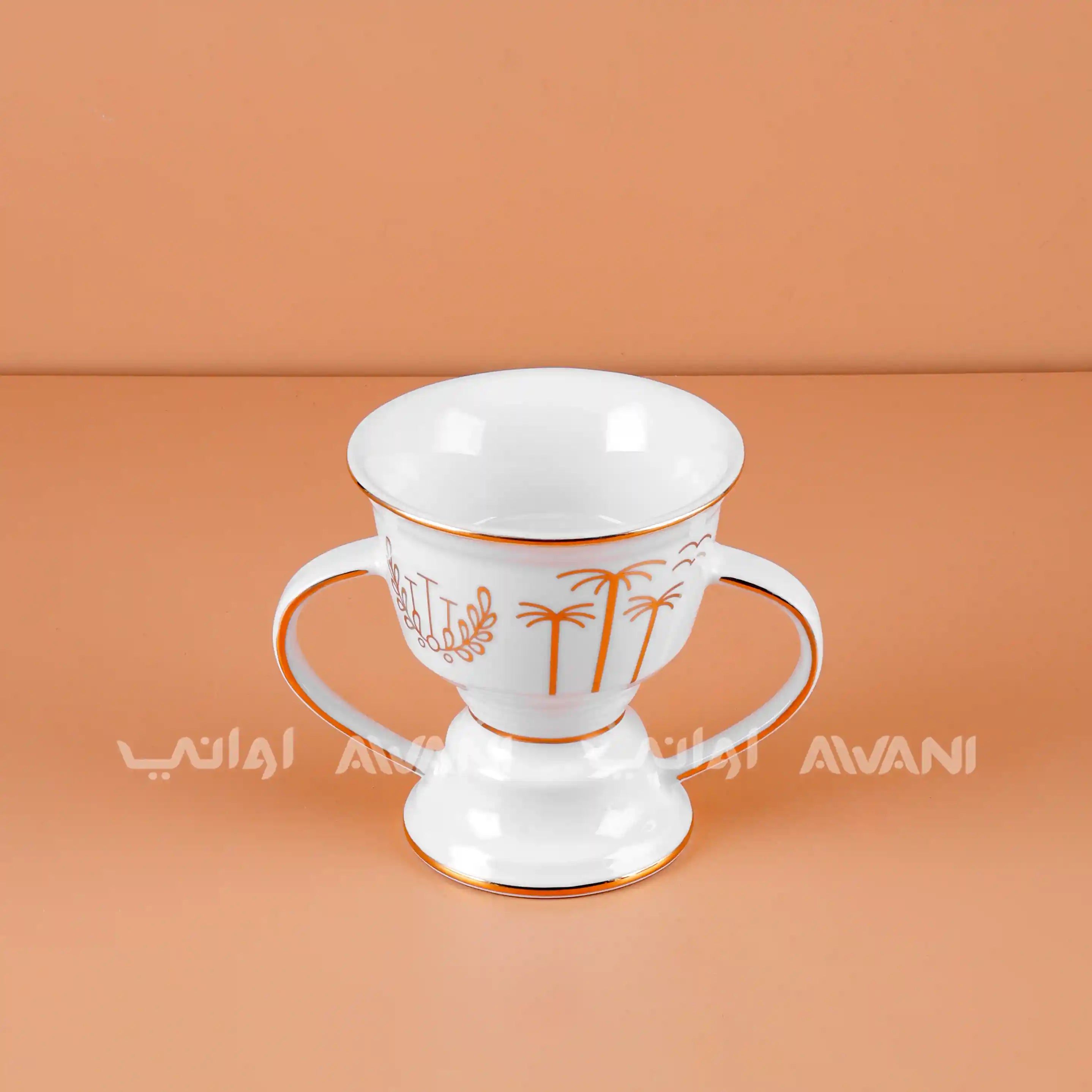 White ceramic cup with gold palm tree design on a peach background