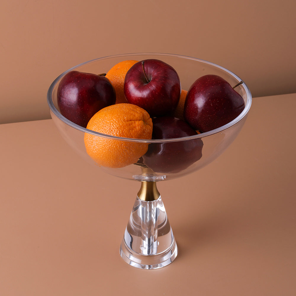 Clear glass fruit bowl with apples and oranges on a beige background