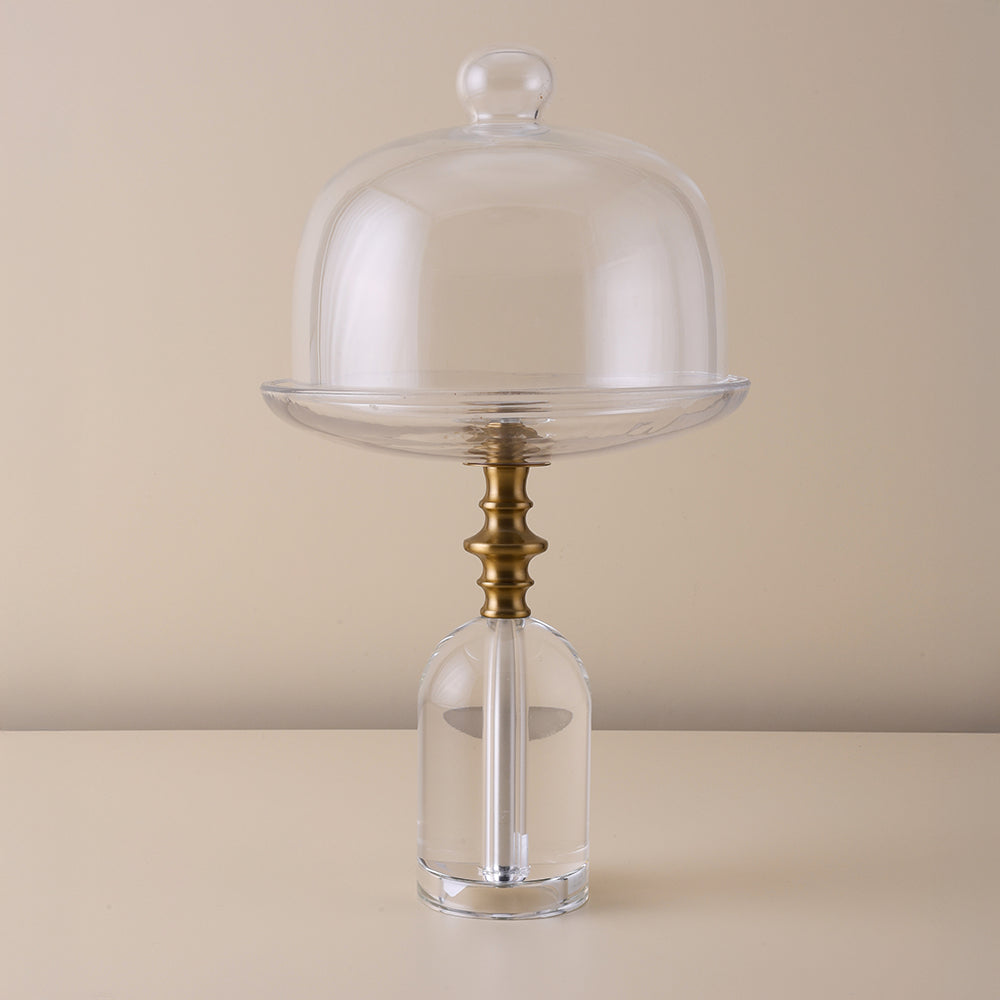 Decorative glass piece with a clear dome and gold base on a beige background